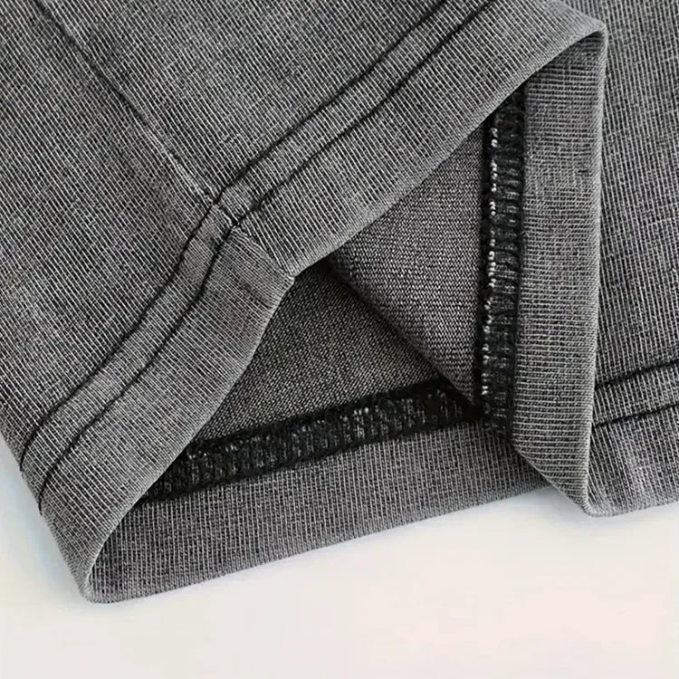 Close-up of grey ribbed fabric with double-stitched hem, highlighting garment quality.