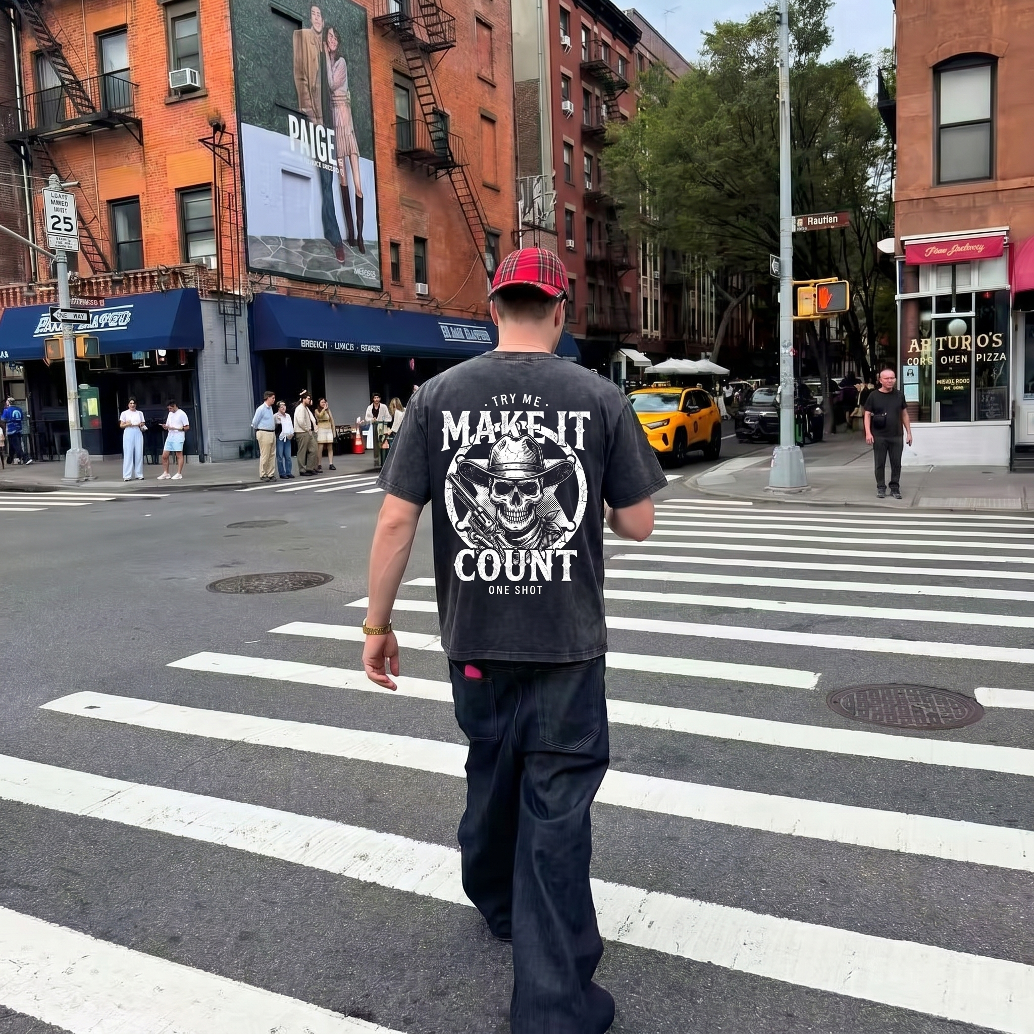Man crossing city street wearing graphic t-shirt with skull, busy urban intersection scene